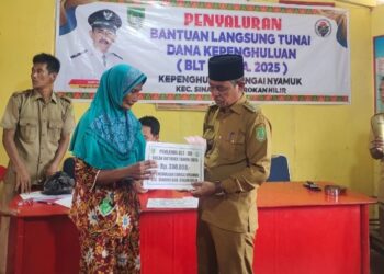 Penghulu Sungai Nyamuk Daryamin tampak sedang membagikan BLT desa kepada salah satu masyarakat (Iwandi)