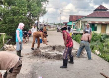 Penghulu Rafika tampak sedang mengaduk Semen dalam kegiatan gotong royong tersebut (f: Iwandi)